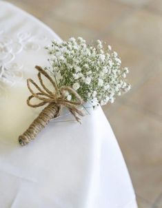 small white flowers in a glass vase tied to a napkin on top of a table