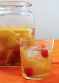 three glasses filled with different types of drinks on top of a white table cloth next to a pitcher