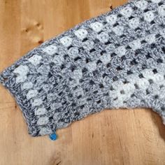 a gray and white crocheted dishcloth on a wooden table