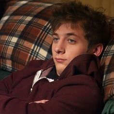 a young man sitting on top of a couch with his arms crossed and looking at the camera