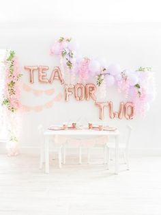 the table is set for two with pink and white balloons