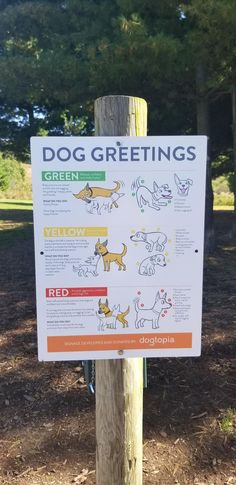 a sign posted on a wooden post in front of some trees and grass, with instructions for dog greetings