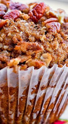 a muffin with pecans and crumbled toppings sitting on a plate