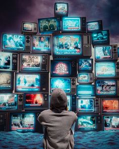 a person standing in front of a wall of tvs with many different types of television screens on them