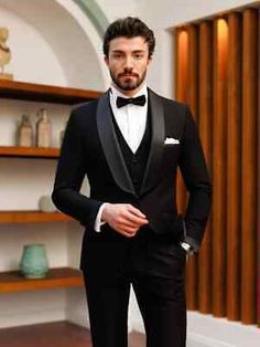 a man in a tuxedo standing next to a bookshelf and shelves