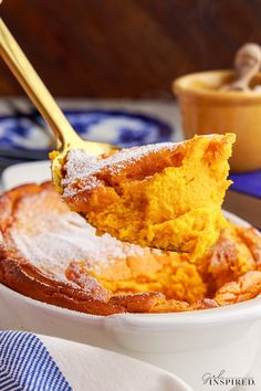 a spoonful of powdered sugar on top of a bowl filled with pumpkin pudding