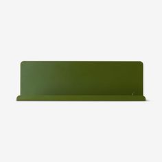 a green shelf sitting on top of a white wall