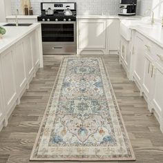 a large rug in the middle of a kitchen with white cabinets and an area rug on the floor