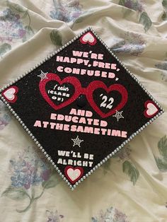 a graduation cap with hearts on it sitting on top of a bed covered in flowers