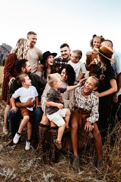 a large group of people are posing for a photo in the grass with one child on his lap