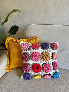 a crocheted pillow sitting on top of a couch next to a potted plant