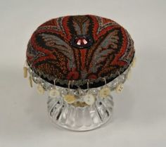 a decorative hat is sitting on top of a glass stand with beads and bead