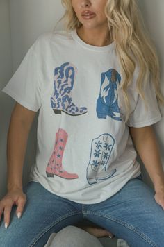 Look stylish in this Cowgirl Boots Graphic Tee. It features a variety of different printed boots printed on a cotton white tee. With a relaxed cut, this shirt was made for the modern Western country lifestyle. cowgirl printed boots graphic white cotton tee relaxed fit premium cotton machine wash cold model is wearing a s/m Cowgirl Boots Graphic, Country Graphic Tees, Graphic Tee Outfit, Printed Boots, Unique Clothes For Women, Western Graphic Tees, Graphic Tee Outfits, Rodeo Outfits, Country Lifestyle