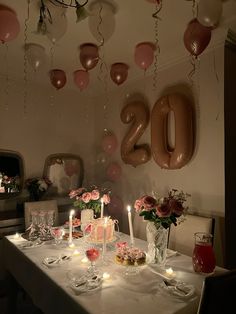 the table is set for a party with balloons and candles in the shape of numbers