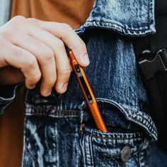 a man holding an orange cell phone in his pocket