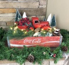 an old coca - cola truck is decorated with pine cones and evergreens for christmas