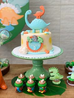 a dinosaur themed birthday cake with fondant decorations on a table next to other toys