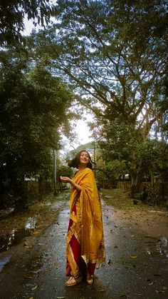 a woman standing in the middle of a road wearing a yellow and red sari