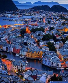 an aerial view of a city at night, with mountains in the backgroud