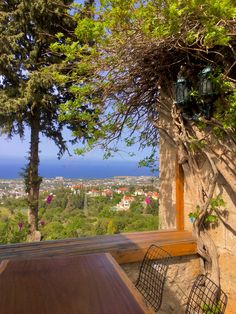 an outdoor table and chairs on a patio overlooking the ocean with trees in the foreground