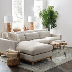 a living room with a large sectional couch and coffee table in front of the window