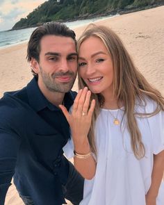 a man standing next to a woman on top of a beach