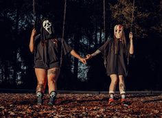 two people wearing masks holding hands on a swing