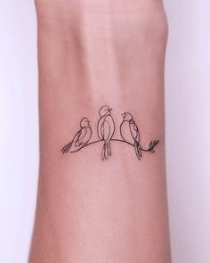 two birds sitting on a branch tattoo on the left side of the wrist, with one bird perched on top of the other