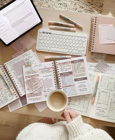 a person sitting at a table with notebooks, pens and paper on top of it