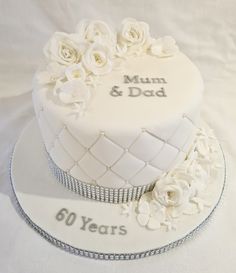 a white wedding cake with flowers on top and the words mum & dad written on it