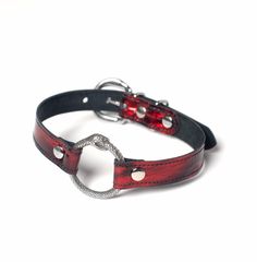 Classic o-ring collar is elevated with an intricate ouroboros snake o-ring and gorgeous black and red patent leather. This leather has a subtle metallic glimmer and is truly special. Fully lined in soft black suede and stitched for strength. Fit is adjustable with buckle. Maybe inspired by House of the Dragon. But dragons are pretty cool Collar is 3/4" wide, with a 1.25" o-ring. SMALL/MEDIUM (11-13")MEDIUM/LARGE (13-15")LARGE/X-LARGE (15-17") Custom sizing available. All pieces are MADE TO ORDER Snake Inspired Fashion, Dragon Choker, Skull Collar, Ring Collar, Ouroboros Snake, Red Choker, O Ring Choker, Fantasy Necklace, Jewelry Wardrobe