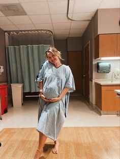 a pregnant woman in a hospital gown is standing on the floor with her belly exposed