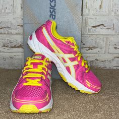 a pair of pink and yellow running shoes sitting on top of a carpeted floor