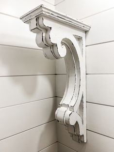 the corner of a white painted wooden wall with an ornately designed bracket on it