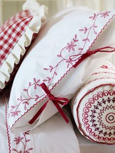 decorative pillows with red and white designs on them sitting on top of a pillow case