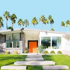 a modern house with palm trees in the front yard and steps leading up to it