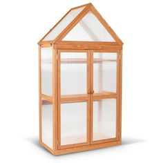 a small wooden greenhouse with glass doors on the front and side windows, in an isolated position