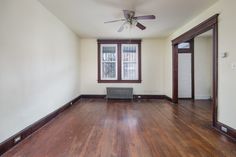 an empty room with hard wood floors and a fan