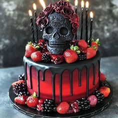 a decorated cake with candles and strawberries on the side, topped with a skull