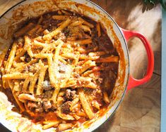 a pot filled with pasta and sauce on top of a wooden table