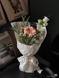 a bouquet of flowers sitting on top of a black table next to books and magazines