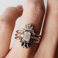 a woman's hand with two rings on it and an engagement ring in the middle