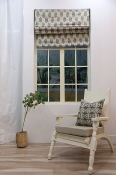 a white chair sitting in front of a window with a potted plant next to it