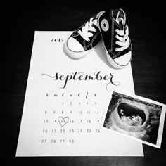 a pair of sneakers sitting on top of a calendar next to a baby's photo