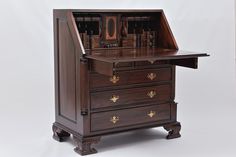 an antique wooden desk with drawers and writing utensils