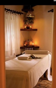 a massage room with candles and towels on the table in front of it is an open door that leads to another room