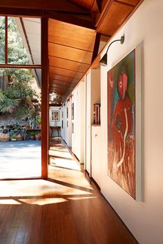 the hallway is lined with paintings and wood flooring