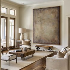 a living room filled with furniture and a large painting hanging on the wall above it