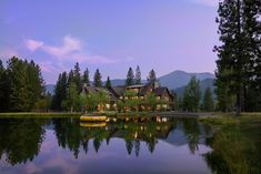 a large house sitting on top of a lush green hillside next to a lake at night