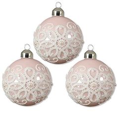 three pink ornaments with white lace on them